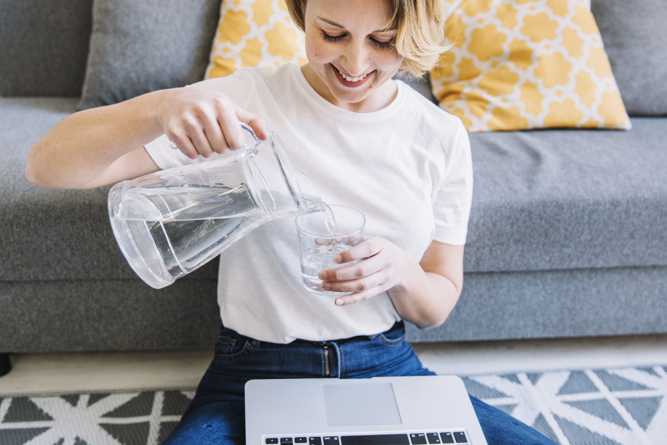 smiling-woman-with-laptop-pouring-water.jpg
